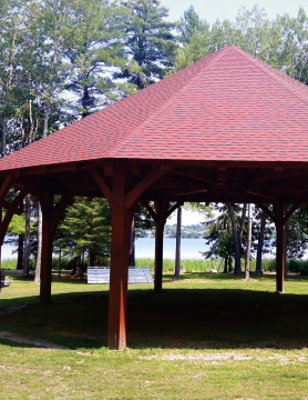 Powwow grounds with the center arbor centered in the picture. There is a lake in the background.